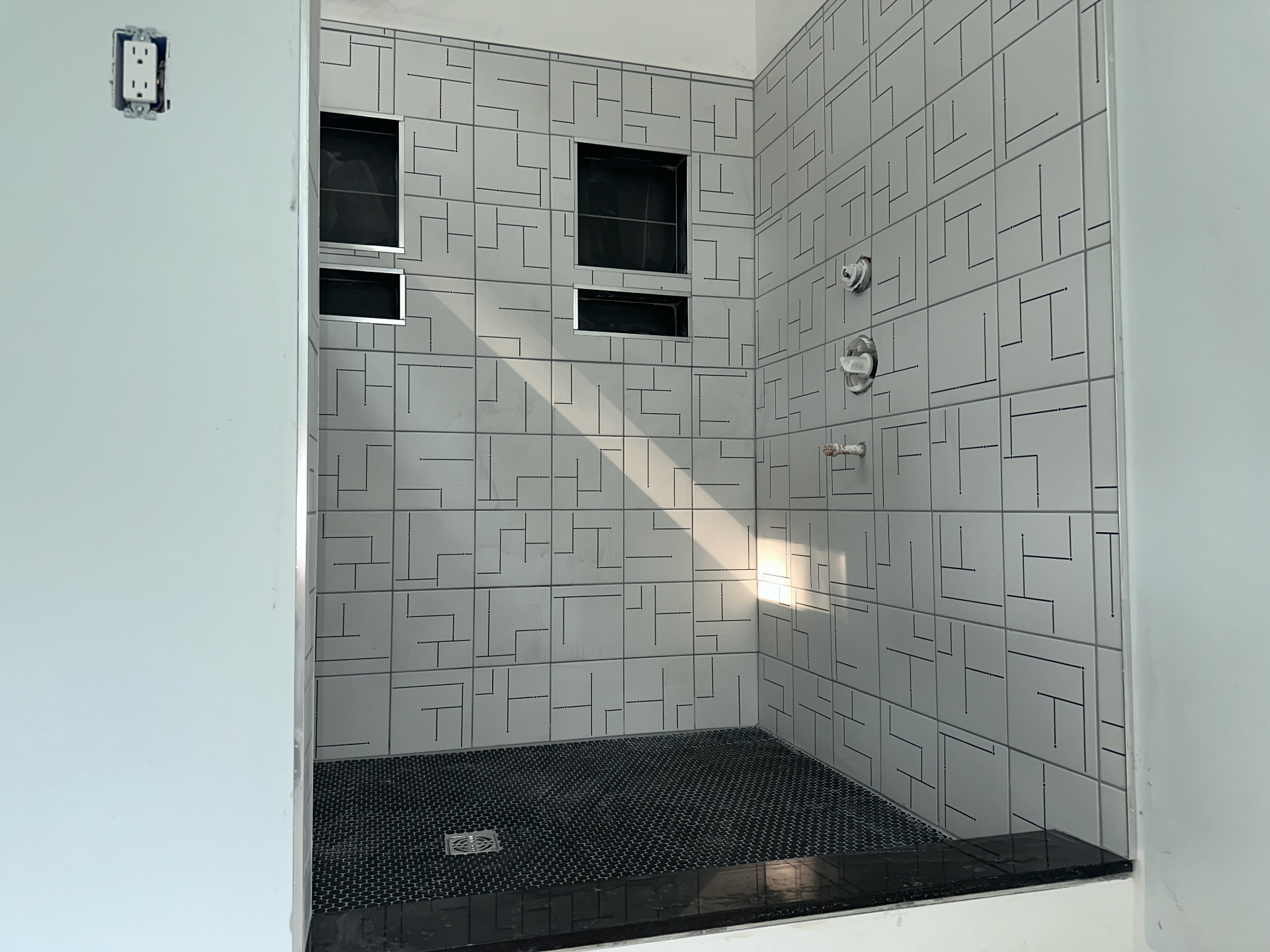 Custom geometric tile shower with black penny mosaic floor